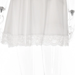 Detail shot of a white mini dress featuring delicate lace trim on the hemline