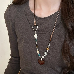 Detail of vintage necklace with brown cord, assorted beads and red heart pendant