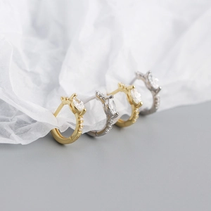 Macro shot of gold and silver S925 huggie earrings with marquise-cut marquise stones