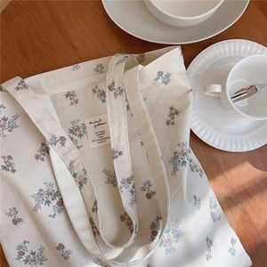 Détail du sac cabas en toile à fleurs avec étiquette sur une table en bois avec café