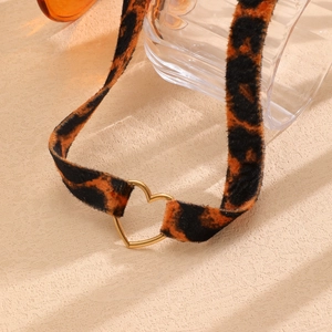 Dettaglio macro del choker in peluche leopardato con ciondolo a cuore in metallo dorato