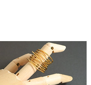 Macro detail of golden spiral multi-layer wrap ring displayed on a wooden mannequin hand