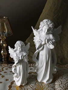 Detalle de dos estatuas de ángeles en resina blanca para decoración acogedora de mesa