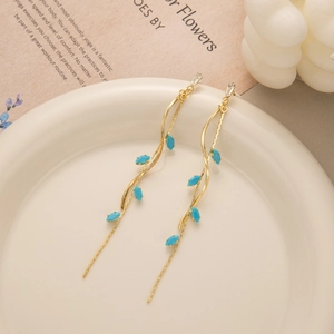 Detail of gold leaf fringe earrings with blue marquise stones on a ceramic tray