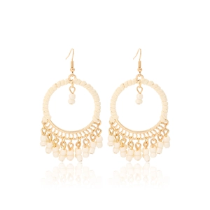 Close-up of bohemian round hoop earrings with cream cotton tassels and resin beads