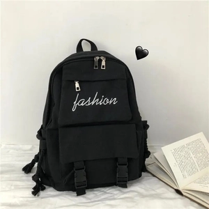 Close-up of black canvas backpack with white fashion embroidery and side cord detail