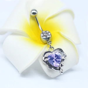 Macro detail of silver navel ring with purple heart pendant resting on a plumeria flower