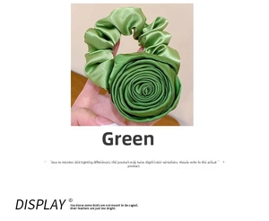 Detail of elegant green satin rose scrunchie with glossy silk-like texture and floral design