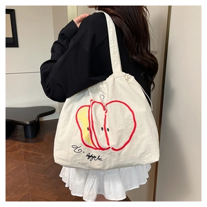 Close-up of artistic apple print and handwritten lettering on white canvas tote bag