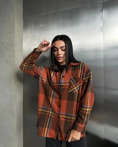 Detail view of orange plaid flannel shirt featuring button cuffs and loose-fit drop shoulder