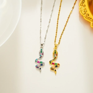 Close-up of gold and silver punk snake necklaces with colorful zircon stones on white