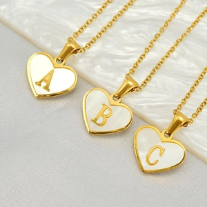 Detail of heart-shaped gold necklaces with white pearl inlay and metal letters A, B, C