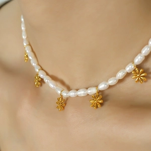 Elegant freshwater pearl necklace featuring gold daisy pendants on a female neck model