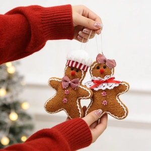 Pair of plush gingerbread man ornaments with chef hat and bow tie held by hands