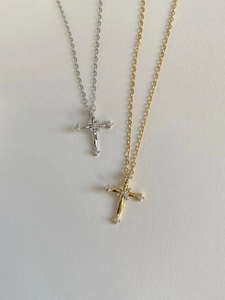Detailed view of silver and gold cross necklaces featuring sparkling cubic zirconia stones