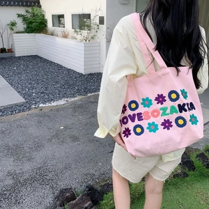 Detail of pink canvas tote bag with floral embroidery and Love So Zakka typography