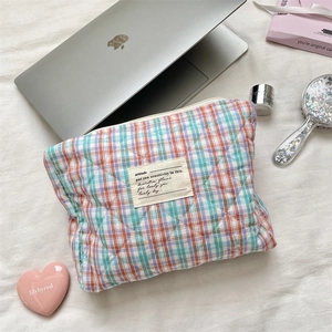 Close-up of quilted plaid cosmetic bag with orange and pink checkered cotton pattern