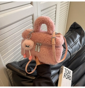 Detailed view of pink plush bucket bag with fuzzy charm and adjustable leather strap