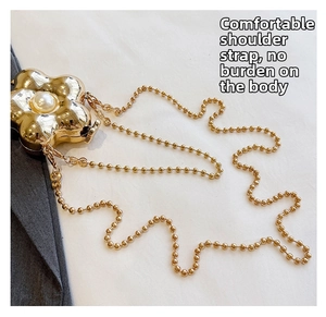 Détail d'un mini sac fleur dorée avec perle nacrée et bandoulière chaîne à billes