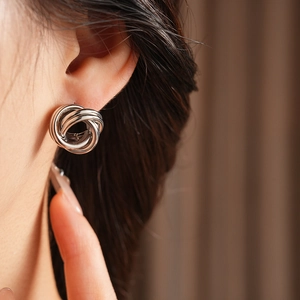 Gros plan de boucles d'oreilles nœuds argentés à plusieurs boucles portées sur un modèle