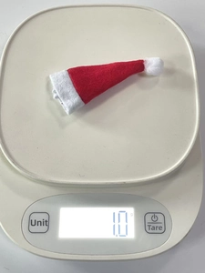 Detailed view of a mini 1.0g red felt Christmas hat on a precise digital scale