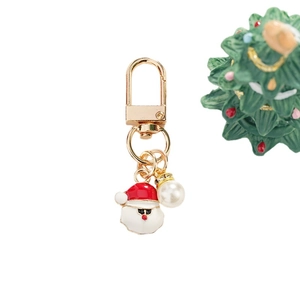 Christmas Santa enamel keychain with large white pearl and gold metal ring on festive background