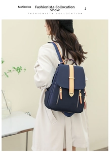 Detail of navy blue nylon backpack with beige zippers shown on a model's back