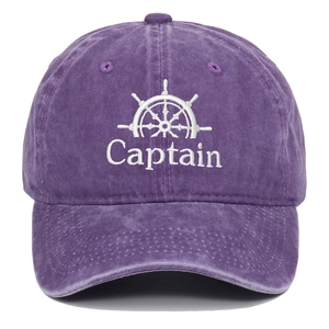 Detail der Captain-Stickerei und des Steuerrads auf einer lila gewaschenen Baseballkappe