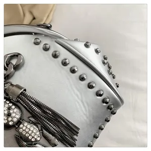 Detail of silver studded shell bag with rhinestone owl charm and metal tassels