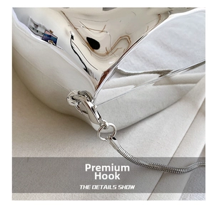 Detail shot of silver metal evening bag featuring a lobster clasp and snake chain link