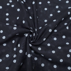 Close-up detail of sheer black polka dot mesh fabric with soft pleated texture