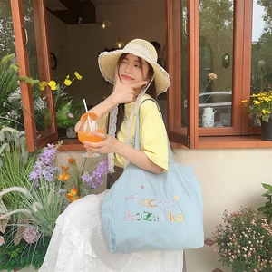 Gros plan d'un cabas en toile bleu clair avec broderie florale colorée Lucky Zakka