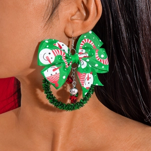 Detail shot of Christmas wreath earrings with green bow and bell charms worn by model