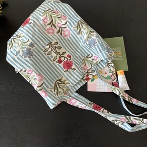 Detail view of blue striped cotton tote bag with delicate pink floral prints
