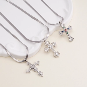 Silver snake chain necklaces with colorful zircon cross pendants on a ceramic plate