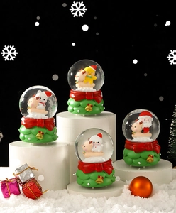 Close-up of festive Christmas snow globes with Santa and snowman on white platforms