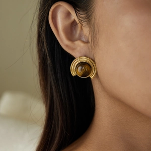 Detail of 18K gold stainless steel earring with brown tiger eye stone on model