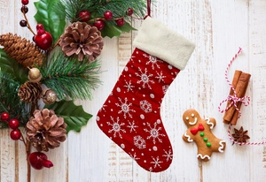 Detail of red Christmas stocking with white snowflake pattern and festive pine decorations