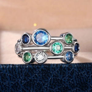 Macro shot of silver ring with inlaid blue, green, and white round gemstones