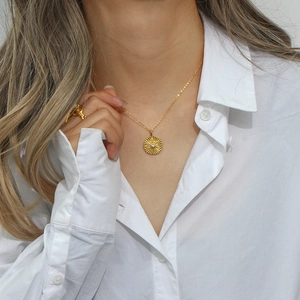 Detail of 18K gold-plated starburst medallion necklace with crystal on female neck