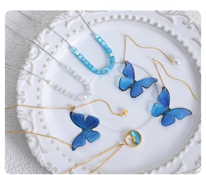 Sammlung von blauen Schmetterlingsketten und Ohrringen auf einer weißen Keramikplatte