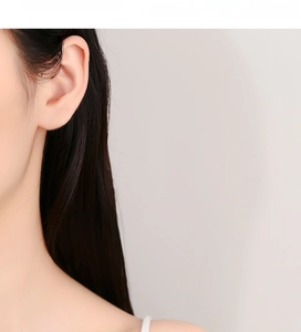 Détail des boucles d'oreilles en argent 925 avec zircon carré portées à l'oreille