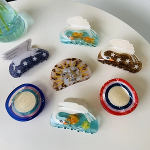 Close-up of assorted acetate star and sun hair claws in vibrant colors on a white surface