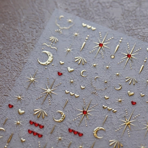 Luxe 3D nail art stickers with gold moon stars and red hearts on minimalist background
