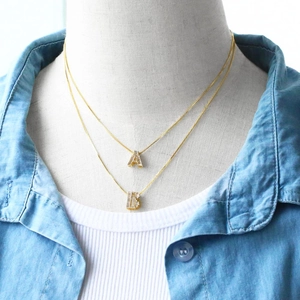 Close-up of layered gold letter A and B necklaces with sparkling cubic zirconia stones