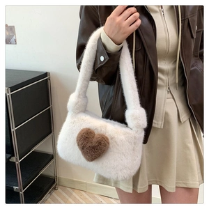Close-up of white plush shoulder bag with a brown heart detail worn by a model