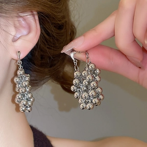 Détail des boucles d'oreilles en grappe de perles argentées au design pendant minimaliste