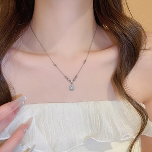 Close-up of elegant stainless steel chain necklace with light blue water drop pendant on model