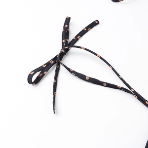 Detailed close-up of a black tie-up knot with orange geometric floral patterns