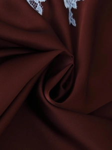 Détail du tissu satiné bordeaux avec texture lisse et bordure en dentelle blanche